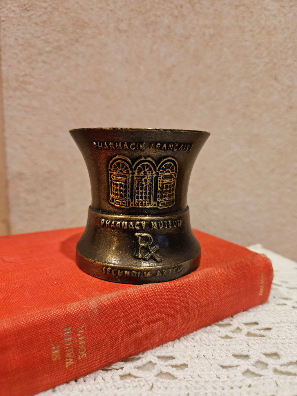 A vintage bronze pharmacy mortar and pestle, a symbol of the pharmacy profession, featuring intricate designs and historical inscriptions.