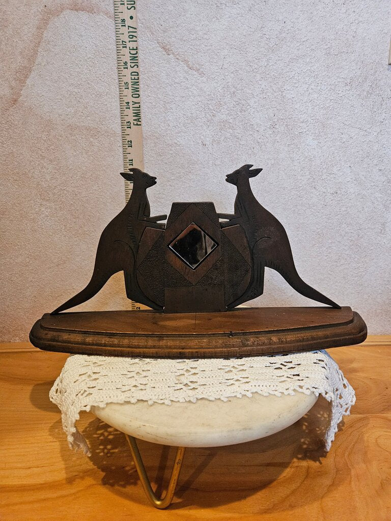 Antique decorative wooden kangaroos flanking central shield-like mirror, resting on a base